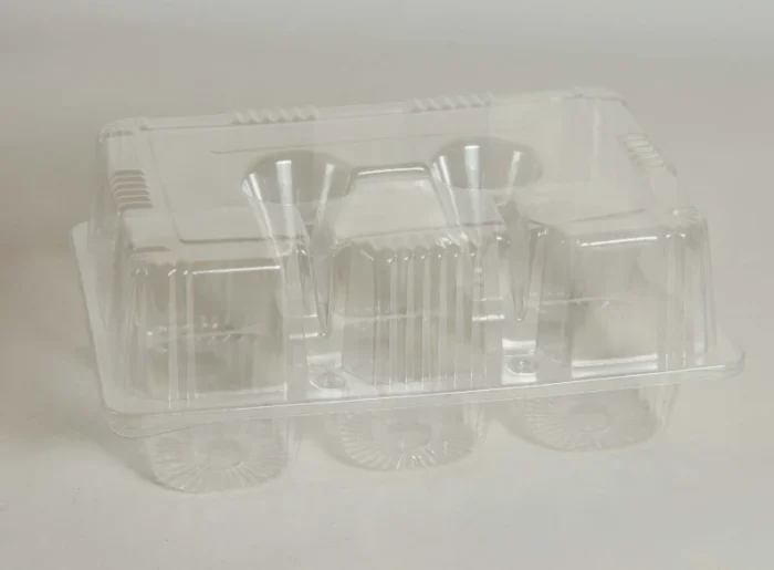 "Empty JC Packaging Six-Muffin Display Case, highlighting its crystal-clear structure and the intricate detailing designed to frame each muffin beautifully."