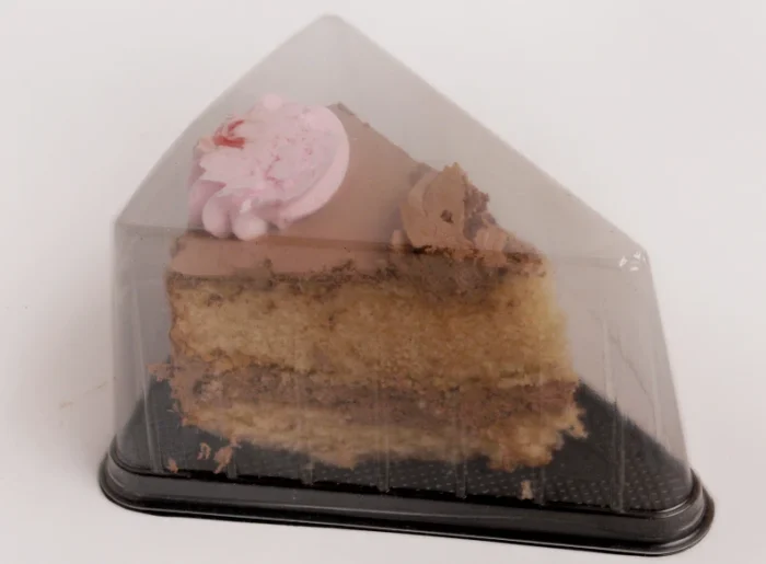 "Chocolate and vanilla layer cake slice with a pink rose icing detail, presented in a triangular clear cake slice packaging from JC Packaging, combining visual appeal with protective design."